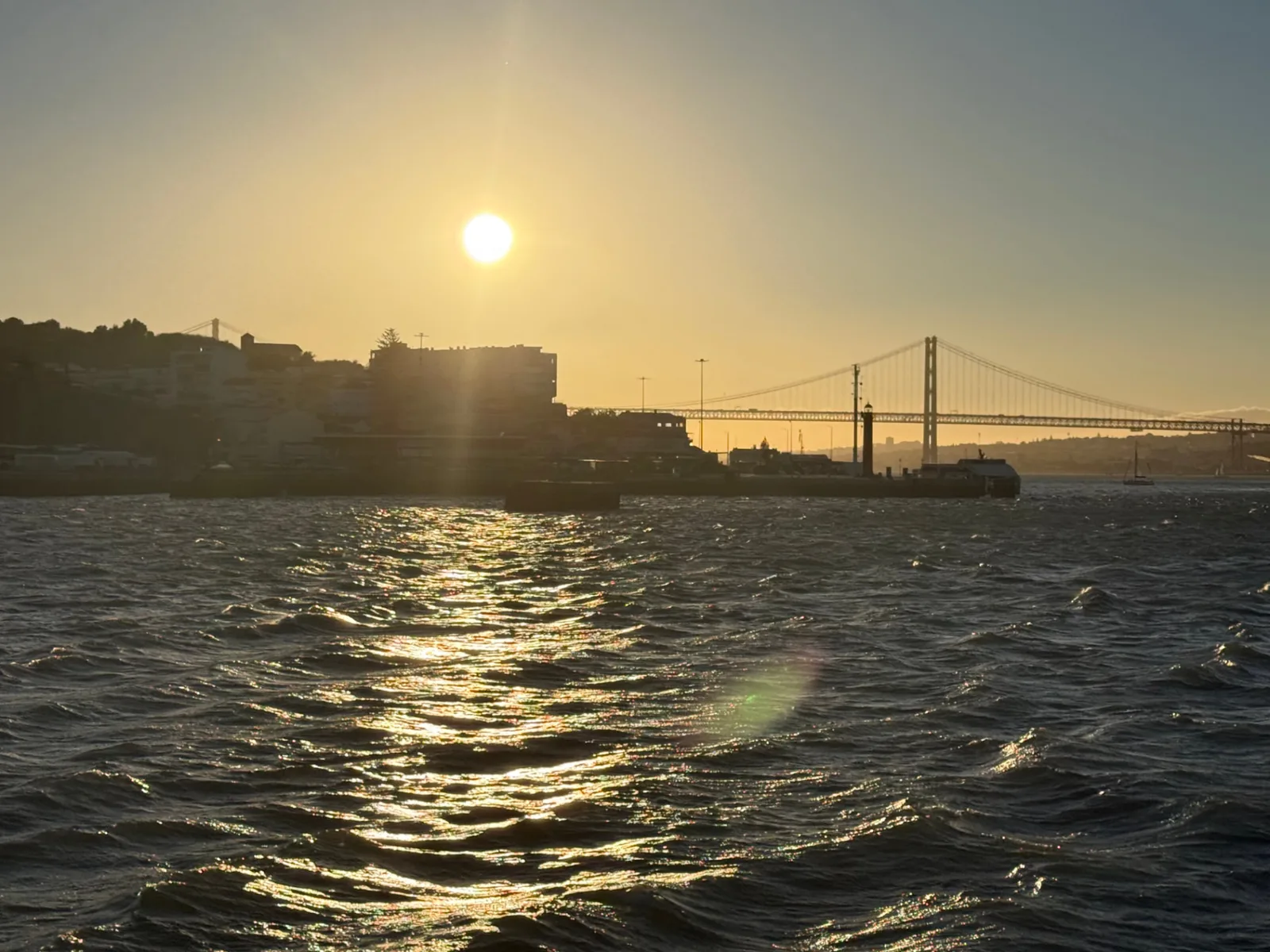 Golden evening light over the Tagus with the 25 de Abril Bridge and a ferry on the river