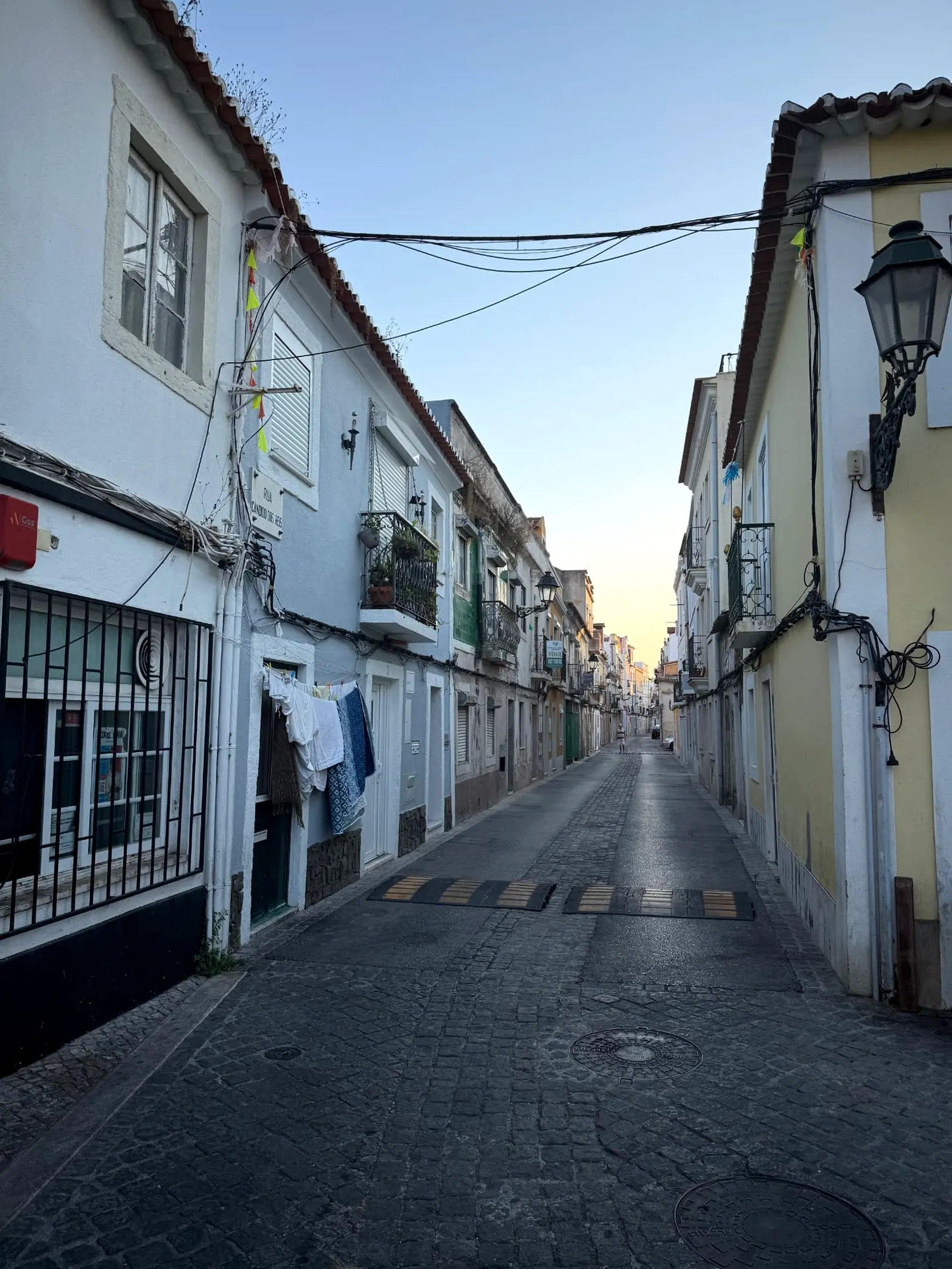 Narrow cobbled lane lined with pastel houses, iron balconies and hanging laundry